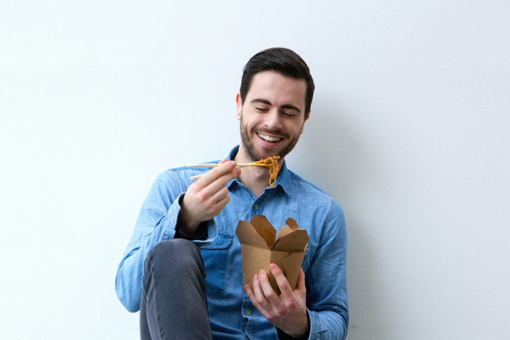 Man smiling with chopsticks and noodles